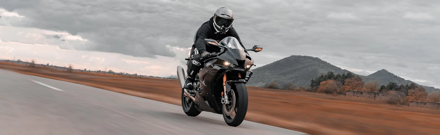 Motard sur une sportive noire en vitesse sur une route de montagne